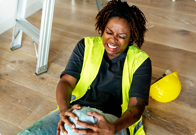 Worker holding injured knee on the floor